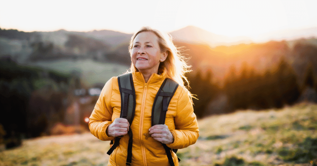 Tax Smart Retirement Webinar Featured Image - Senior woman hiking, with the sun rising in the background behind a mountain.